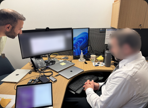 Two people meeting in an office with multiple computers